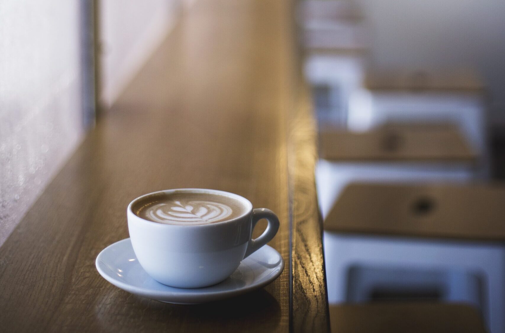 A vertical closeup shot of white cup of latte art coffee on a window shelf in a cafe